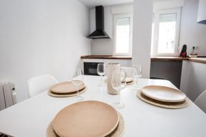 a white table with two plates and wine glasses at Joya en el corazón de Ribeira in Ribeira