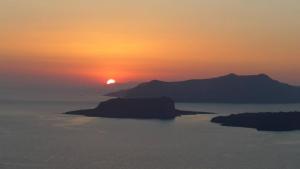 zachód słońca nad wodą z górą w obiekcie Spectacular view Caldera St V w mieście Megalochori