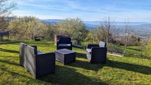 3 sillas y una mesa en un campo con vistas en Domaine de la Griffe - Chambres d'hôtes à la montagne, en La Roche-sur-Foron