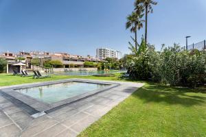 una piscina en un parque con césped y palmeras en Villa Verano en San Miguel de Abona