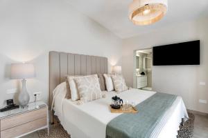 a white bedroom with a large bed with a television at Villa Verano in San Miguel de Abona +34 photos