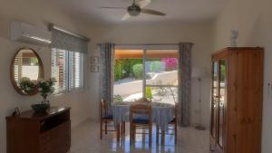 a dining room with a table and chairs and a window at Villa Best Holiday- breathtaking sea views, amazing garden, private pool, BBQ, next to CORAL BAY, Lower Peyia, Paphos in Peyia