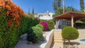 un jardín con arbustos y flores y una valla en Villa Best Holiday- breathtaking sea views, amazing garden, private pool, BBQ, next to CORAL BAY, Lower Peyia, Paphos en Peyia