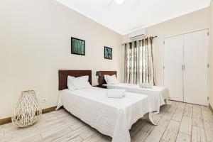 Ce lit se trouve dans un dortoir doté de murs blancs et de parquet. dans l'établissement By The Sea Algarve Golden Properties, à Armação de Pêra