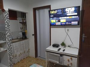 Habitación con TV en la pared y cocina. en Refugio Piratininga 201 en Niterói
