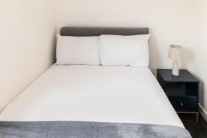 een slaapkamer met een bed met witte lakens en een lamp bij Host & Stay - Anfield Hideaway in Liverpool