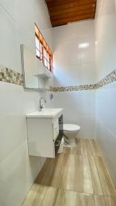 La salle de bains blanche est pourvue d'un lavabo et de toilettes. dans l'établissement Reserve Temporada - Chácara 01, à Olímpia