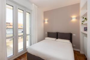 uma cama branca num quarto com uma grande janela em Gaffurio Apartments em Milão