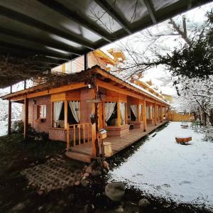 une maison avec une grande terrasse en bois dans la neige dans l'établissement Santos Lugares Cabañas, à Junín de los Andes