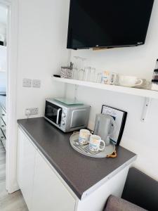 a kitchen counter with a microwave and two coffee mugs at The Mudeford Gem Accommdation in Christchurch