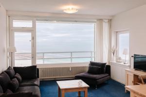 sala de estar con sofá, sillas y ventana grande en De Steltloper en Zandvoort