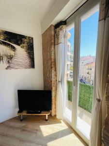 a living room with a tv and a large window at Joyau rare port de Nice in Nice