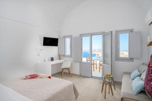 a white room with a bed and a view of the ocean at Spectacular view Caldera St Μ in Megalochori