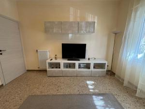 a living room with a television on a white cabinet at New apartment next to the sea in Bordighera