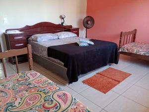 a bedroom with a bed and a table and a chair at Apt. de Setiba - HOSPEDARIA OCA RUCA in Guarapari