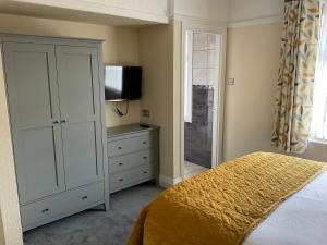 um quarto com uma cama e uma cómoda com uma televisão em Cornerways Llandudno em Llandudno