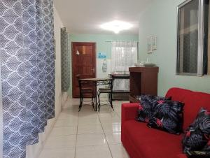 Apt. de Setiba - HOSPEDARIA OCA RUCA في غواراباري: غرفة معيشة مع أريكة حمراء وطاولة