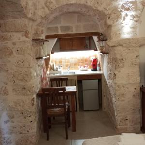 eine Küche mit einem Tisch und einem Waschbecken in einer Steinwand in der Unterkunft Sotto la pergola in San Michele Salentino