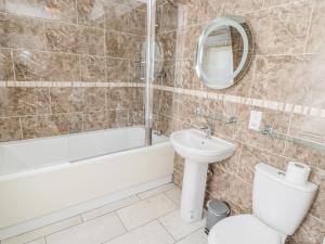 a bathroom with a toilet and a bath tub and a sink at Jubilee House in Alnwick