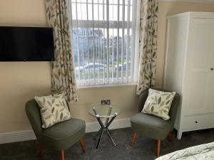 um quarto com 2 cadeiras, uma mesa e uma janela em Cornerways Llandudno em Llandudno