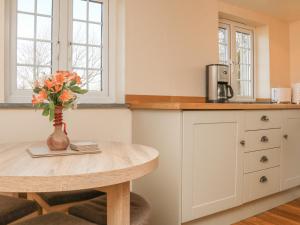 uma cozinha com uma mesa e um vaso com flores em The Linhay em Holsworthy