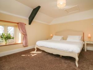 a bedroom with a white bed and a window at The Linhay in Holsworthy