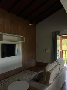 a living room with a couch and a flat screen tv at Terras Claras Pousada e Lazer in Alfredo Chaves