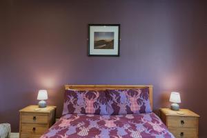 a bedroom with a purple bed with two night stands at Kilchrist Castle Cottages in Campbeltown