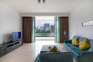 un salon avec un canapé bleu et une télévision dans l'établissement A Chic & Comfy 3BR EmbassyView Suite FREE Parking, à Kuala Lumpur