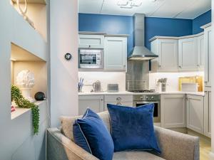 a kitchen with blue walls and a couch with blue pillows at The Linen Mill Apartment Pass the Keys in Belfast