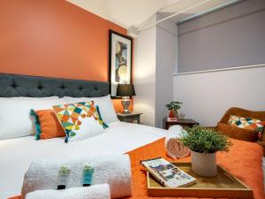 a bedroom with a bed with an orange accent wall at The Linen Mill Apartment Pass the Keys in Belfast