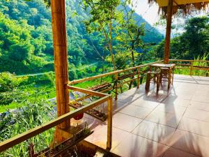 un balcón de una casa con mesa y sillas en Pu Luong Riverside Lodge, en Hương Bá Thước