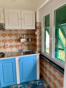a kitchen with blue cabinets and a sink and a window at casa fiorella in San Bernardino
