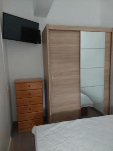 een slaapkamer met een bed, een dressoir en een televisie bij Casa Paulinho in Portimão