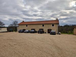 a building with cars parked in a gravel parking lot at Chambres d'hôtes du Vigeant in Le Vigeant