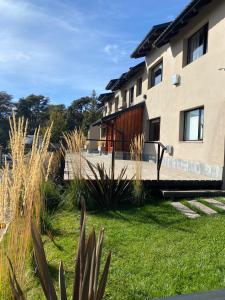 a building with a yard with plants in front of it at Complejo Quillaipe Apart Suite in San Carlos de Bariloche