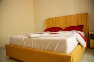 キガリにあるTWINKLE Appartmentsのベッド1台(上に赤い枕2つ付)