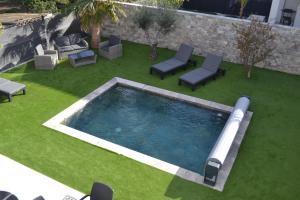 a swimming pool on a lawn with lounge chairs and sidx sidx sidx at ETOILE DU BERGER Saint Aygulf 3 Villas et 4 appartements jardin individuel et piscine chauffée - la mer et les plages 450 m in Saint-Aygulf