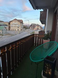 a green chair sitting on a balcony with a street at COSTALUNGAHOUSE TrekkingBikeSki selfcheck-in apartment in Carezza al Lago