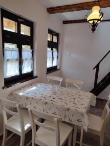 jadalnia ze stołem, krzesłami i oknami w obiekcie Szent Iván Vendégház w mieście Tata