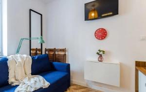 - un canapé bleu dans le salon avec un réveil dans l'établissement Mikroapartament w centrum, à Poznań
