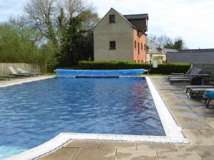 a large swimming pool with a house in the background at Kingfisher House in Somerford Keynes