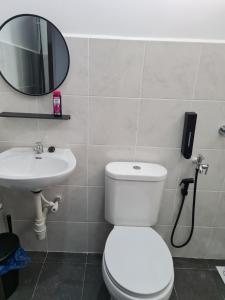 La salle de bains est pourvue de toilettes, d'un lavabo et d'un miroir. dans l'établissement The Bunga and The Daun Housestay 2, à Sungai Besar