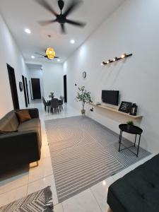 - un salon avec un canapé et un ventilateur de plafond dans l'établissement The Bunga and The Daun Housestay 2, à Sungai Besar