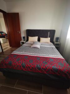 a bedroom with a bed with a red and black comforter at Casa la Grenadine in Esmoriz