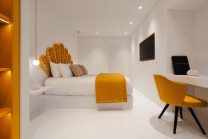 een slaapkamer met een bed, een bureau en een gele stoel bij Croco Mykonos in Tourlos