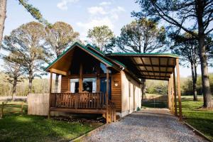 a small cabin with a porch in a park at Lucky Lodge ViP Cabin Lake Guntersville Pet Friendly Fully Fenced Boat Parking Private in Guntersville