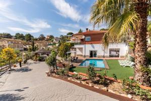 a villa with a swimming pool and a palm tree at Villa Paraíso in Vidreres