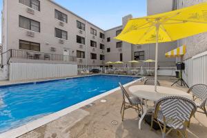 a pool with a table and chairs and an umbrella at Oceanic Hotel & Barefoot Tiki Bar in Wildwood