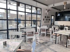 un restaurant avec des tables blanches, des chaises et des fenêtres dans l'établissement Travelers Calm Stay With Free Wi-Fi Near Beach, à Dar es Salaam